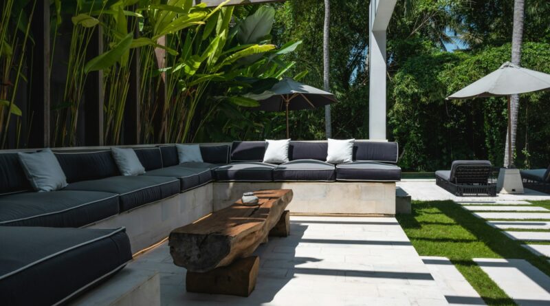 An outdoor living area with a couch, table and umbrellas